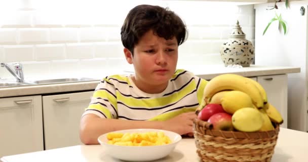 Мальчик-подросток выбирает между фруктами и чипсами 3 — стоковое видео