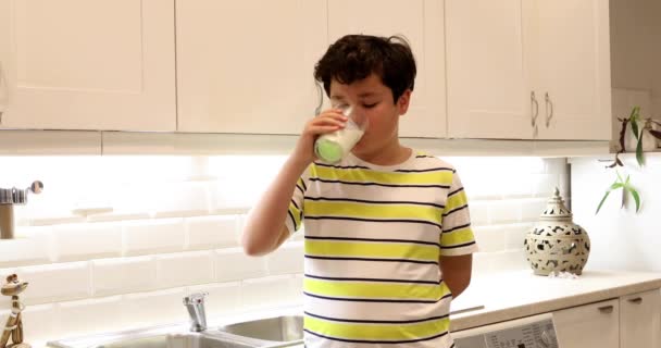 Tini fiú iszik egy pohár tejet a konyhában — Stock videók