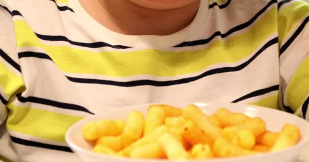 Мальчик-подросток ест сырные закуски на кухне — стоковое видео