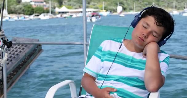 Retrato de un niño joven con auriculares en barco — Vídeos de Stock