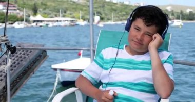 Genç çocuk 3 numaralı teknede müzik dinliyor.