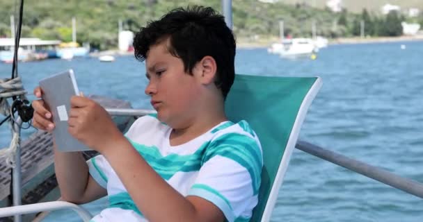 Jeune garçon utilisant une tablette numérique sur yacht 2 — Video