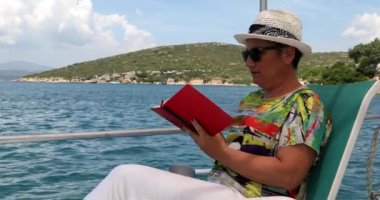 2. Yaz tatilinde teknede kitap okuyan bir kadın.