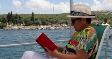 Yaz tatilinde teknede kitap okuyan bir kadın.