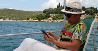 2. Yaz tatilinde yatta akıllı telefon kullanan bir kadın.