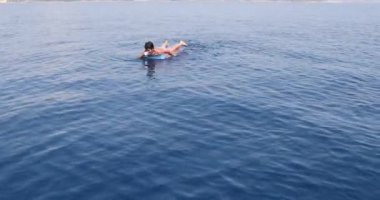 Denizde oynayan şişme yatakta genç çocuk 8