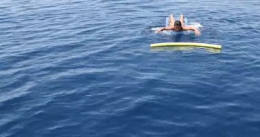 Denizde oynayan şişme yatakta genç çocuk