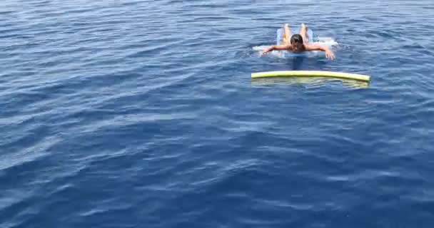 Tiener jongen op de opblaasbare matras spelen op de zee — Stockvideo