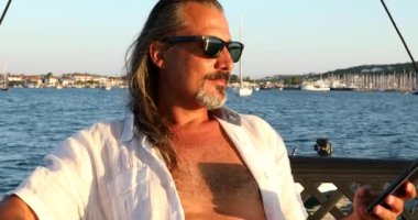 Yat güvertesinde yaz tatilinde telefonda konuşan adam