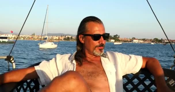 Uomo rilassante sul ponte dello yacht e controllare il suo telefono in vacanza estiva — Video Stock