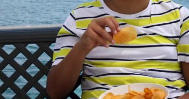 Genç çocuk yaz aylarında yat güvertesinde patates cipsi yiyor 2
