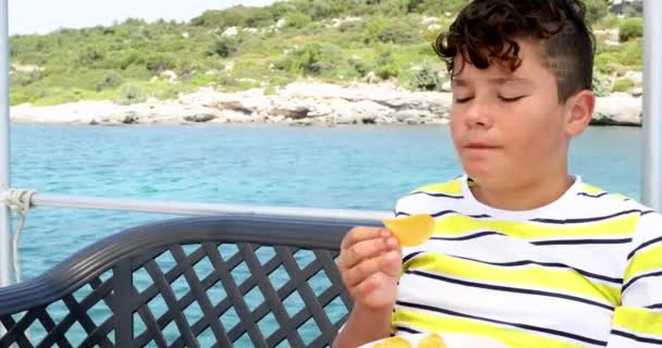 Jonge jongen eten aardappelchips op jacht dek in de zomer 4 — Stockvideo