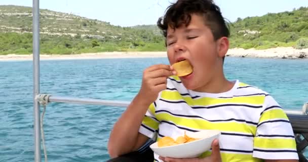 Young boy eating potato chips on yacht deck at summer time 5 — Stock Video