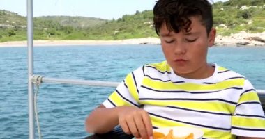Genç çocuk yaz aylarında yat güvertesinde patates cipsi yiyor 6