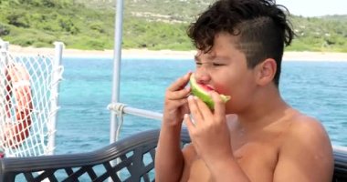 Yat güvertesinde karpuz yiyen genç çocuk 7