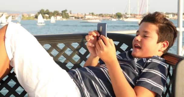 Ребенок на палубе яхты с помощью смартфона 6 — стоковое видео