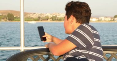 Yaz tatilinde telefon 4 ile selfie fotoğrafı çeken genç çocuk