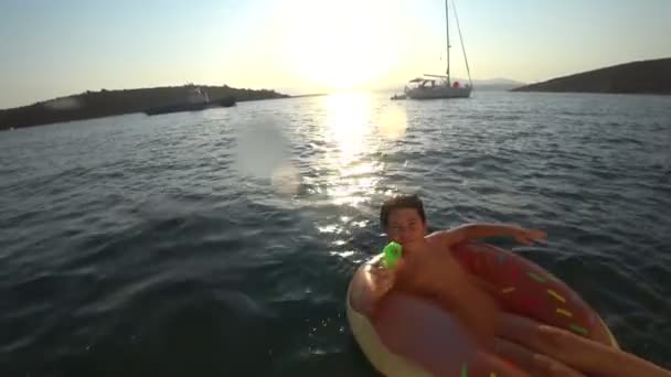 Young boy on air matress shooting with water gun to camera 4 — Stock Video