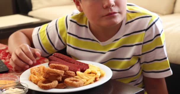 Niño con plato de comida rápida viendo la televisión en casa — Vídeos de Stock