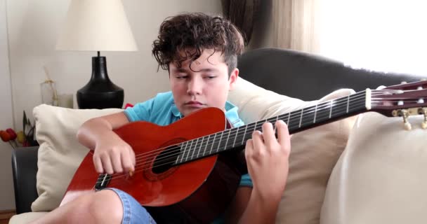 Мальчик играет на классической гитаре дома — стоковое видео