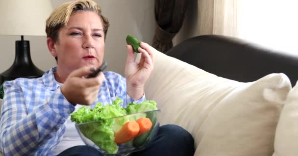 Retrato de una mujer comiendo alimentos frescos y viendo la televisión en casa 2 — Vídeo de stock
