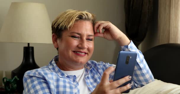 Žena sedí na pohovce a používá chytrý telefon doma — Stock video