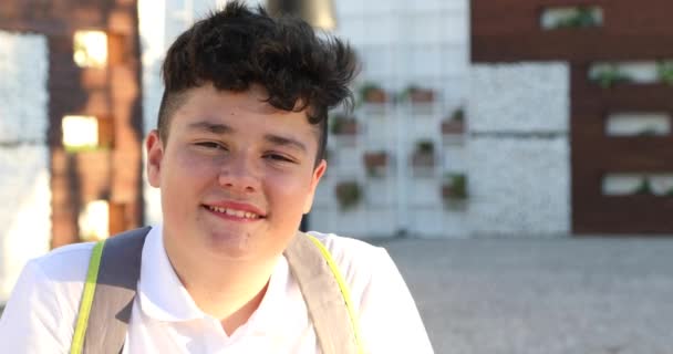 屋外でカメラと笑顔を探してヘッドフォンを持つ幸せな10代の男の子の肖像 — ストック動画