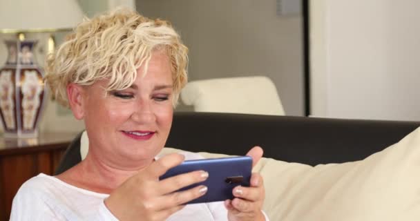 Mulher Meia Idade Sentada Sofá Usando Telefone Inteligente Casa — Vídeo de Stock