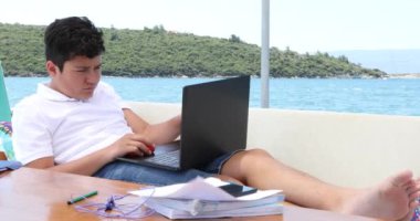 Yat güvertesinde okuyan genç çocuk, karantina ya da tecrit sırasında evde eğitim gören çocuklar için eğitim mesafesi öğreniyor.