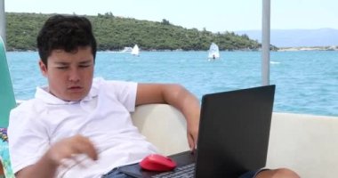 Yat güvertesinde okuyan genç çocuk, karantina ya da tecrit sırasında evde eğitim gören çocuklar için eğitim mesafesi öğreniyor.