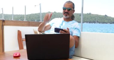 Yakışıklı, esmer adam lüks yat güvertesinde dinleniyor ve yaz tatilinde selfie çekiyor.