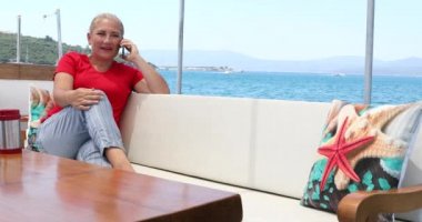 Yaz tatili boyunca cep telefonuyla konuşan kadın.
