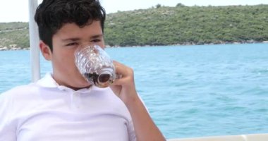 Beyaz çocuk sıcak yaz gününde Yat güvertesinde serinletici soğuk buzlu çay