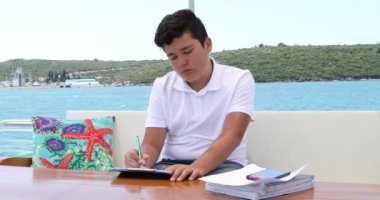 Yat güvertesindeki genç çocuk ders çalışıyor. Mesafe eğitimi kavramı.