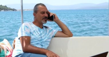 İspanyol bir turistin portresi. Lüks bir yatta. Yaz tatilinde telefonla konuşuyor.