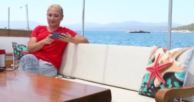 Beyaz tenli sarışın kadın yaz teknesi seyahati sırasında selfie çekiyor.