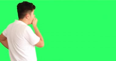 Yeşil arka plan karşısında şaşırmış bir gencin portresi büyük gözlerle kameraya bakıyor.