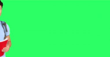 Yeşil arka planda kameraya başparmak gösteren mutlu okul çocuğu