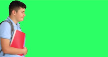 Yeşil arka planda kameraya başparmak gösteren mutlu okul çocuğu