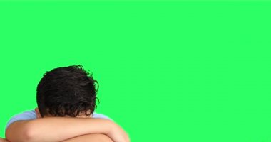 Kollarını yeşil ekran arkasına saklayan korkmuş genç bir çocuk.