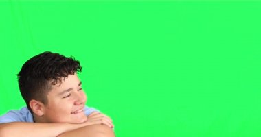 Yakışıklı delikanlı yeşil arka plana karşı kameraya bakıyor ve gülümsüyor.