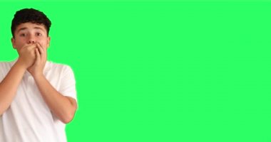 Yeşil arka plan karşısında şaşırmış bir gencin portresi büyük gözlerle kameraya bakıyor.