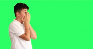 Yeşil arka plan karşısında şaşırmış bir gencin portresi büyük gözlerle kameraya bakıyor.