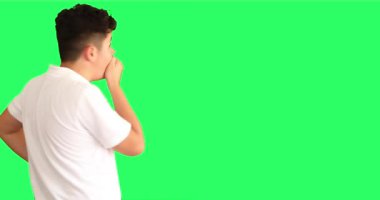 Yeşil arka plan karşısında şaşırmış bir gencin portresi büyük gözlerle kameraya bakıyor.