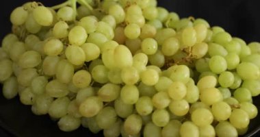 Siyah arkaplanda dönen beyaz olgun üzümler