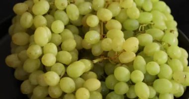 Siyah arkaplanda dönen beyaz olgun üzümler