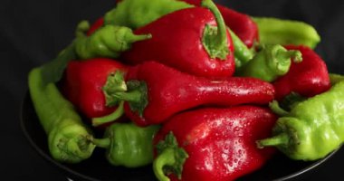 Siyah arkaplanda dönen kırmızı ve yeşil biber