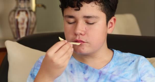 脸上长粉刺的少年坐在沙发上 油腻地吃着油腻的小吃 — 图库视频影像