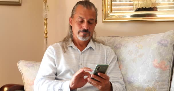 Retrato Hombre Hispano Mediana Edad Sentado Sofá Usando Teléfono Inteligente — Vídeos de Stock