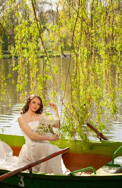 Fantasy portrait of elegant bride in white wedding dress boating on river